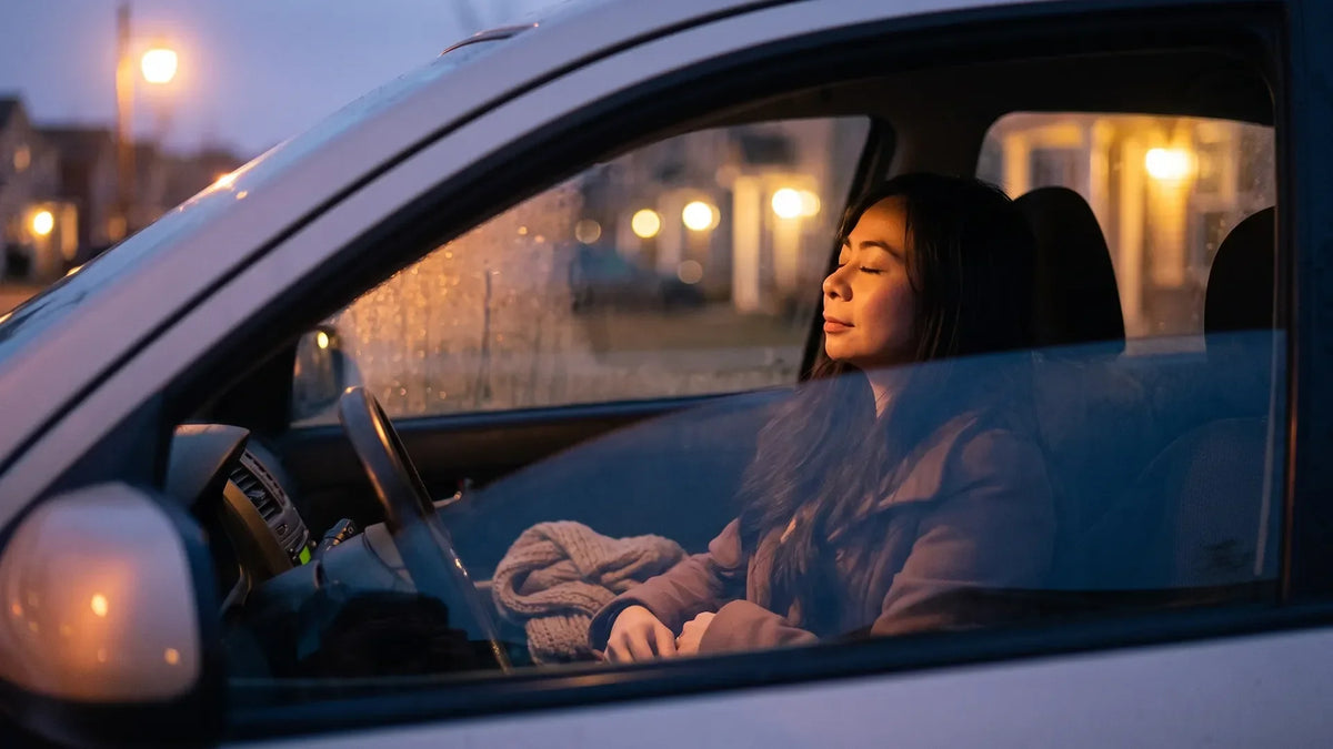Introverted empath resting alone in a parked car at dusk after a gathering
