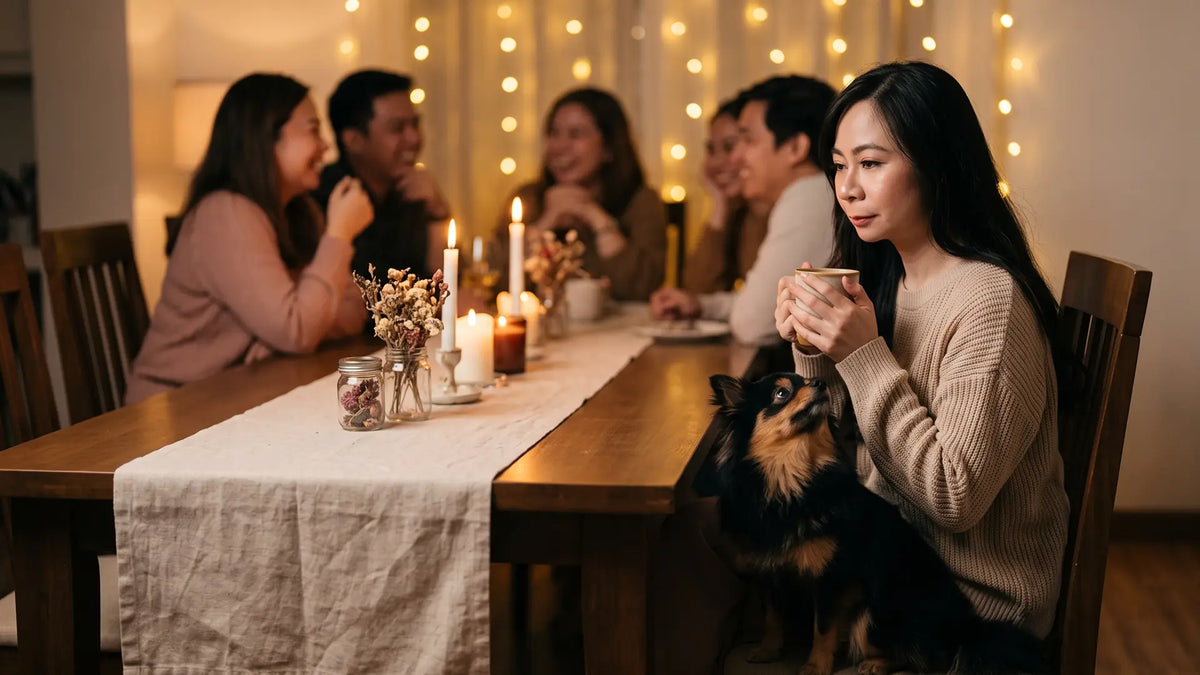 Woman holding a mug at the quiet end of a candlelit dinner table as Munchkin sits looking up at her