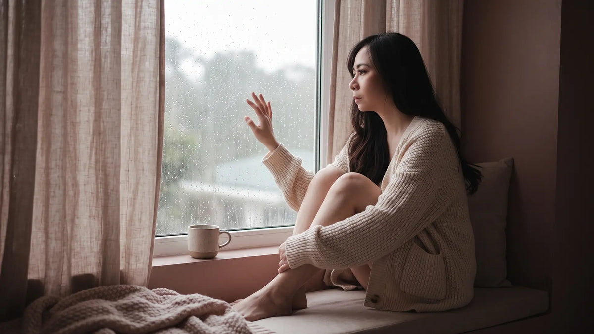 Sensitive woman resting by a rainy window, quiet and drifting, unhealthy INFP signs